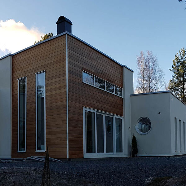 Höga mörka aluminiumfönster på en modern villa med träpanel