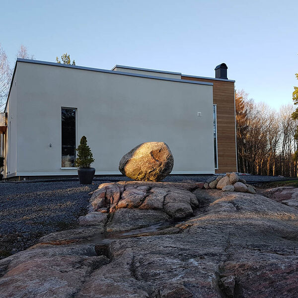 Vitt modernt hus med fasta aluminiumfönster på en berghäll