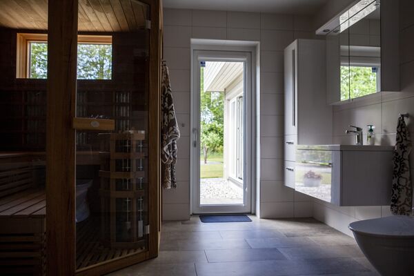 Badrum med bastu och vit helglasad dörr ut mot trädgården