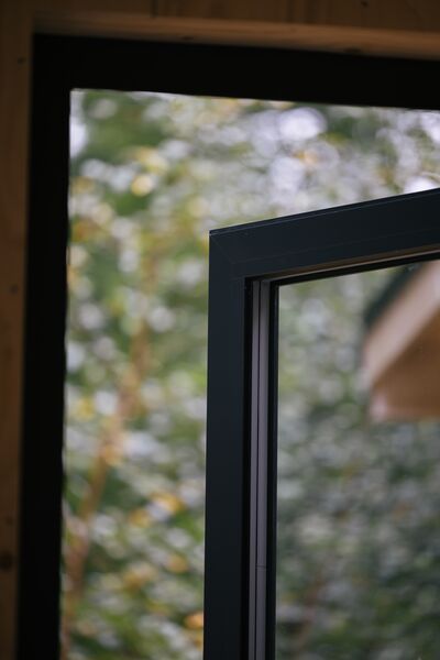 Närbild på en slank antracitgrå profil på en öppen fönsterdörr
