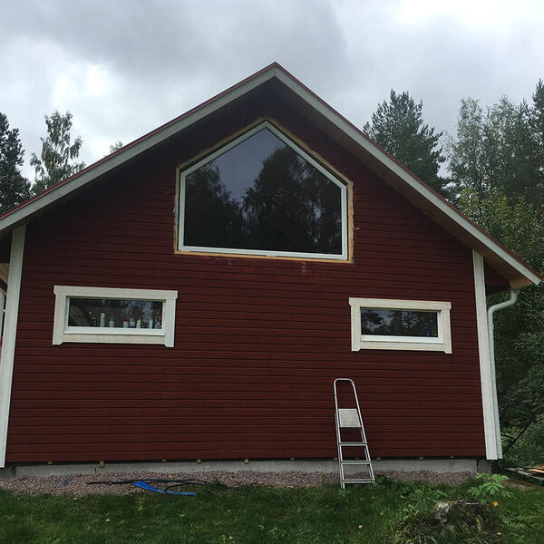 Fast fönster i vinkel i gavelspetsen på ett rött hus