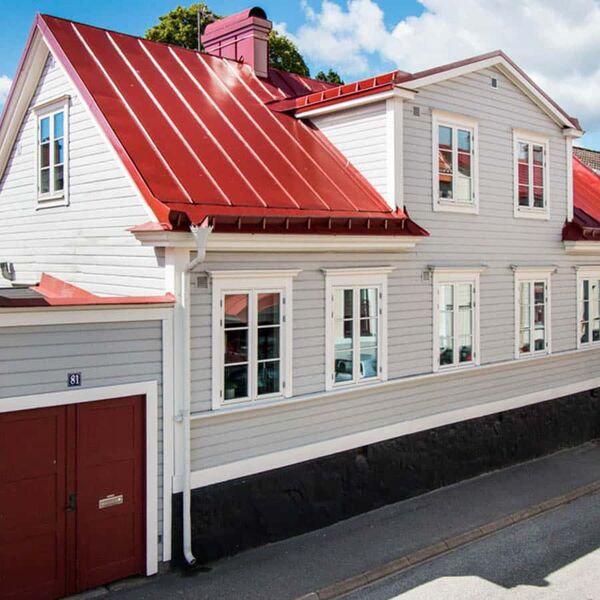Vita sidohängda träfönster i två luft med duplexspröjs på vitt hus med rött plåttak