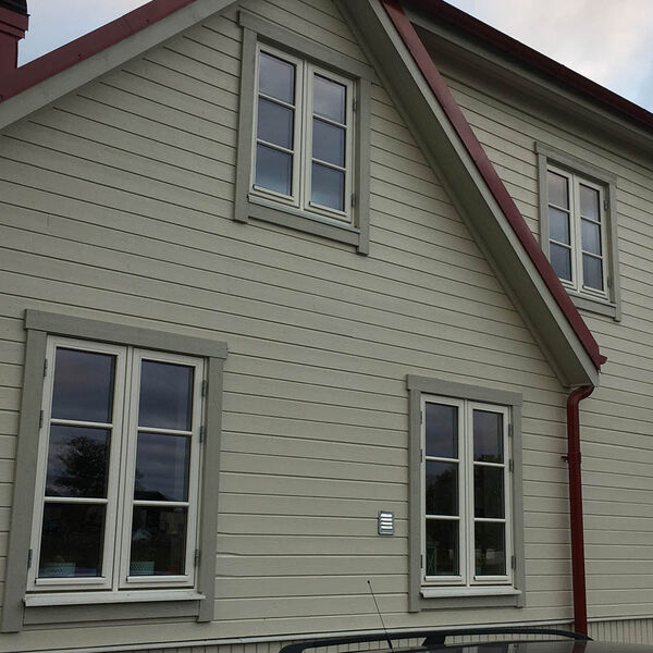Två sidohängda spröjsade träfönster på grön träfasad
