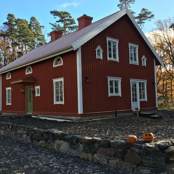 Vita spröjsade träfönster på ett rött tvåvånings trähus