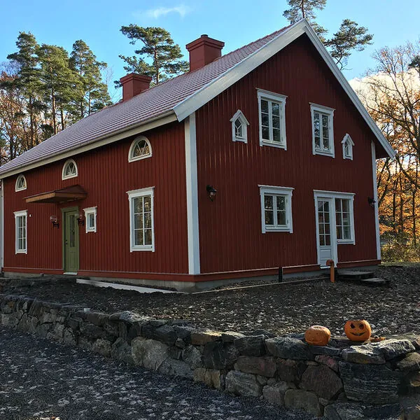 Vita spröjsade träfönster på ett rött tvåvånings trähus